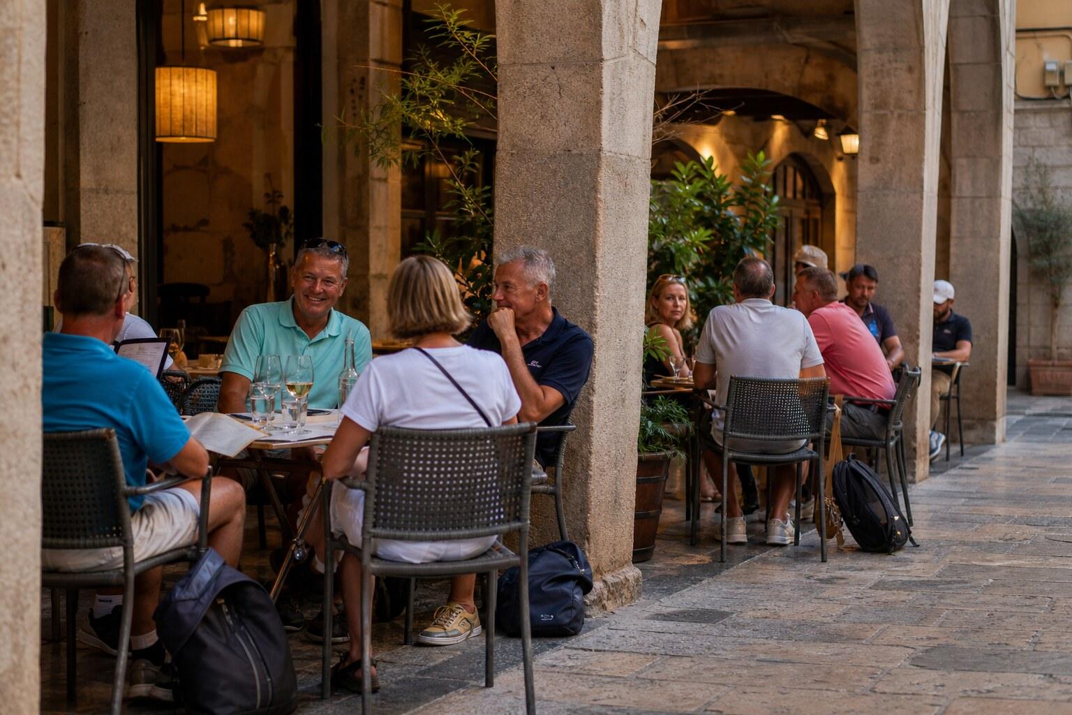 Golf visitors dining beneath stone arcades in Girona old town