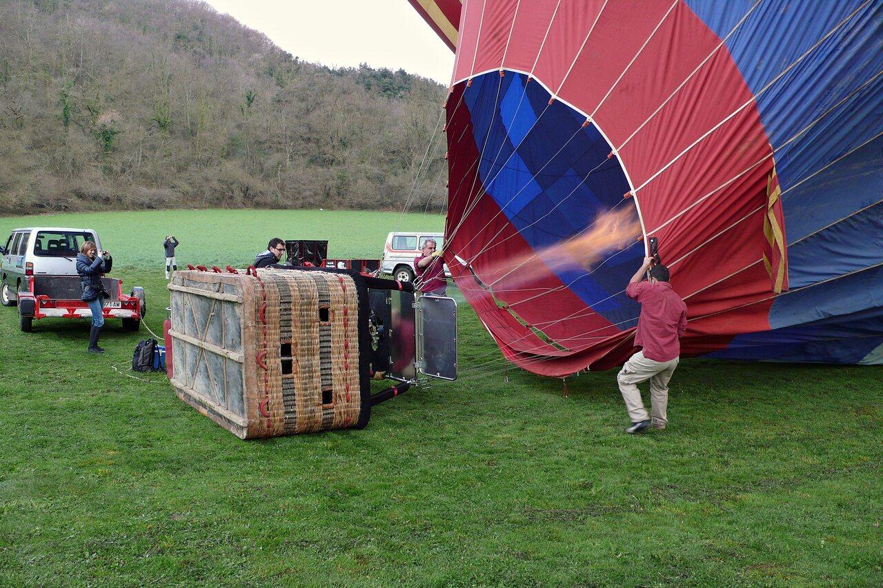 Ground crew handling a balloon envelope and basket in a La Garrotxa field